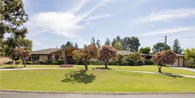 view of front facade featuring driveway, a front lawn, and stucco siding