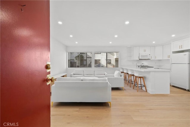 living room with light wood-style flooring and recessed lighting