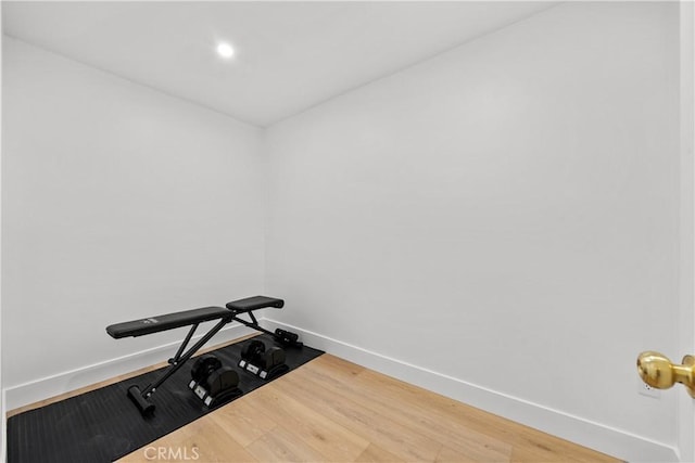 exercise room featuring baseboards, wood finished floors, and recessed lighting