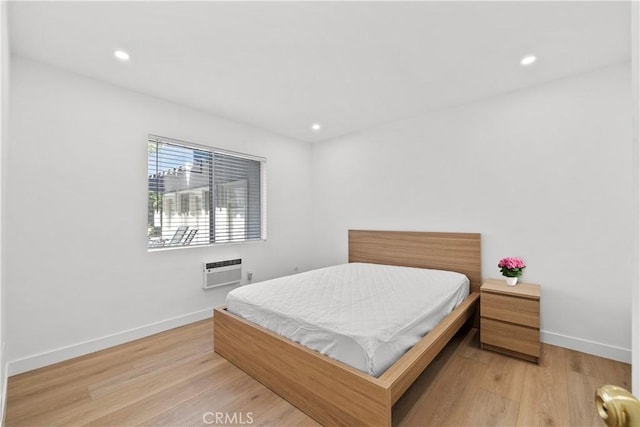 bedroom with recessed lighting, baseboards, a wall mounted AC, and light wood-style flooring