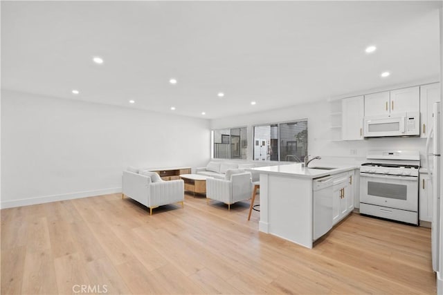 kitchen with recessed lighting, a sink, white appliances, a peninsula, and open floor plan