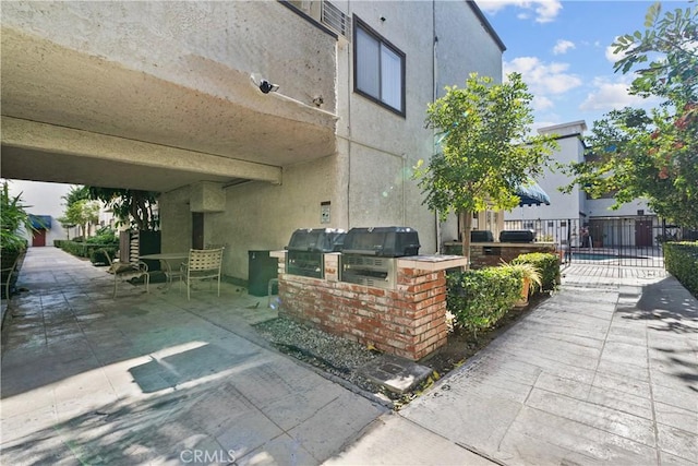 exterior space with a grill, fence, and exterior kitchen