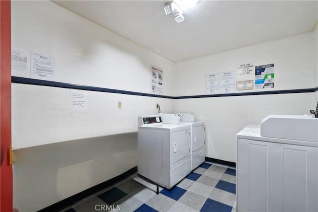 community laundry room featuring light floors, washer and dryer, and baseboards