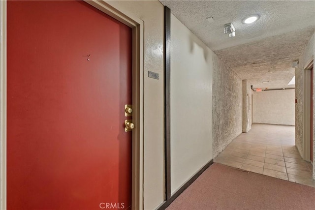 corridor featuring carpet floors, tile patterned flooring, and a textured ceiling