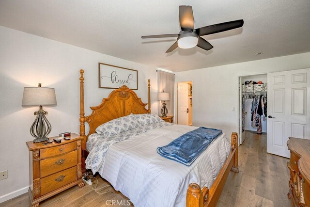 6030 Treehaven Ct, Lancaster, CA 93536 - bedroom featuring wood finished floors, a walk in closet, a closet, ceiling fan, and baseboards