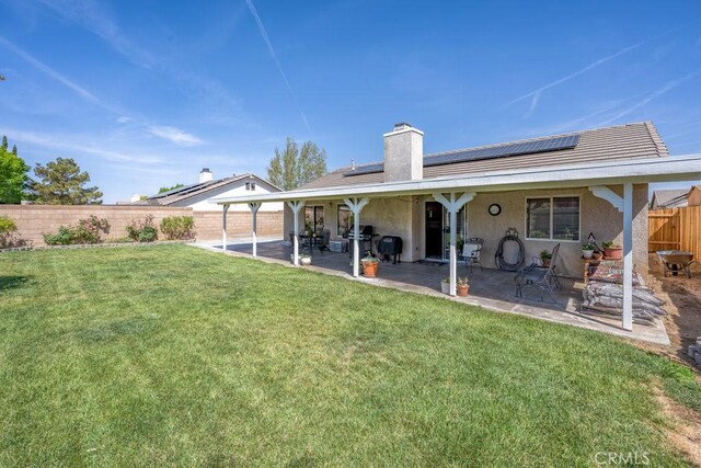 6030 Treehaven Ct, Lancaster, CA 93536 - rear view of property with a patio area, roof mounted solar panels, stucco siding, and a chimney