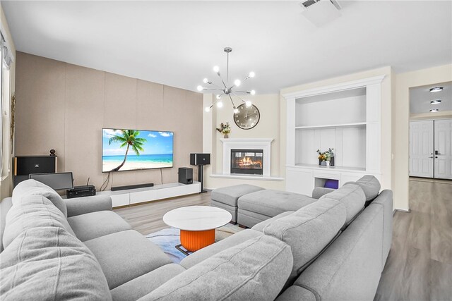 13608 Sagemont Ct, Eastvale, CA 92880 - living room with wood finished floors, a chandelier, built in shelves, and a glass covered fireplace