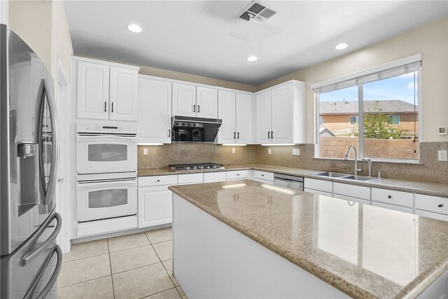 13608 Sagemont Ct, Eastvale, CA 92880 - kitchen featuring appliances with stainless steel finishes, a kitchen island, white cabinets, tasteful backsplash, and recessed lighting