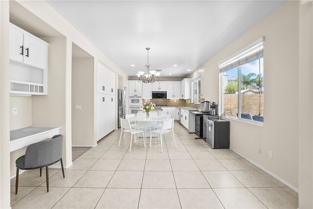 13608 Sagemont Ct, Eastvale, CA 92880 - kitchen featuring a chandelier, black microwave, white oven, decorative backsplash, and white cabinetry