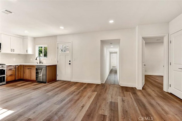 kitchen with stainless steel appliances, light countertops, visible vents, and light wood-style floors