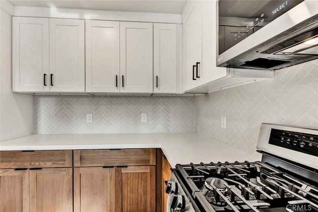 kitchen with backsplash, appliances with stainless steel finishes, white cabinetry, and light countertops