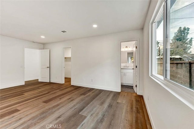 unfurnished bedroom featuring visible vents, baseboards, wood finished floors, and multiple windows