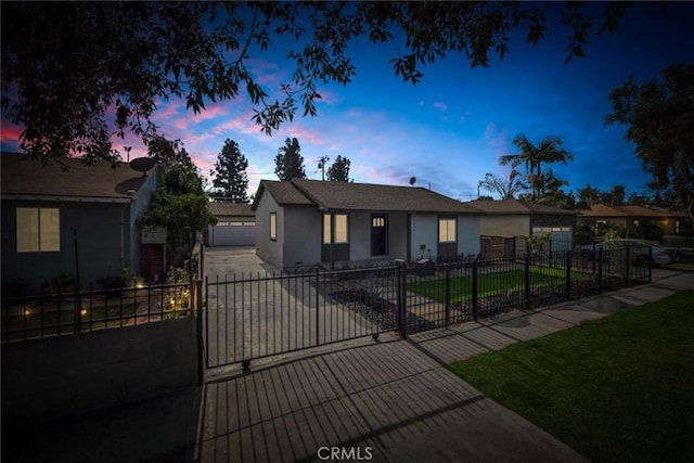 ranch-style house with a fenced front yard, driveway, a garage, a lawn, and stucco siding