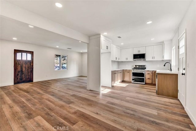 kitchen with stainless steel appliances, light wood-style floors, open floor plan, and recessed lighting