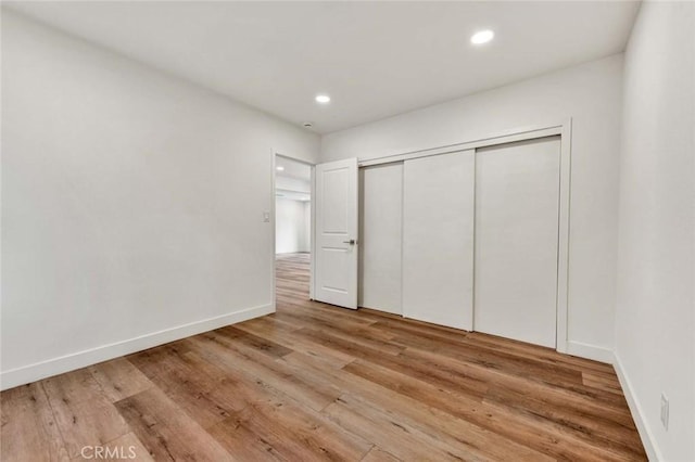 unfurnished bedroom featuring recessed lighting, light wood-type flooring, a closet, and baseboards