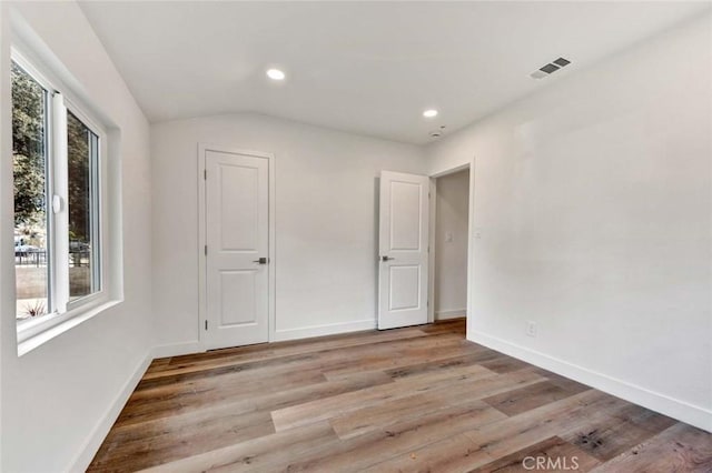 unfurnished bedroom with light wood-style flooring, baseboards, visible vents, recessed lighting, and lofted ceiling