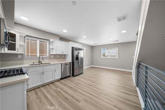 3721 S San Pedro St, Los Angeles, CA 90011 - kitchen with open shelves, a sink, light countertops, appliances with stainless steel finishes, and visible vents