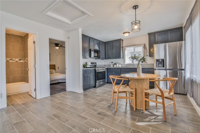 kitchen featuring baseboards, appliances with stainless steel finishes, pendant lighting, and light countertops