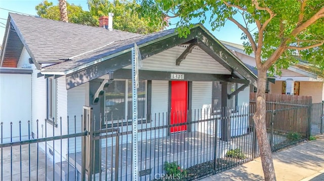 bungalow-style house with a gate, roof with shingles, a porch, and a fenced front yard