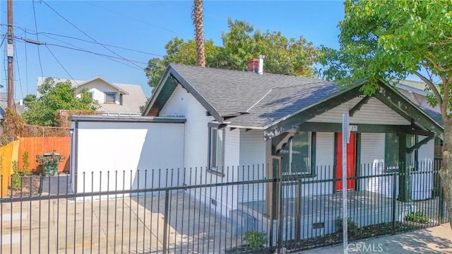 bungalow-style house featuring roof with shingles, a porch, and a fenced front yard