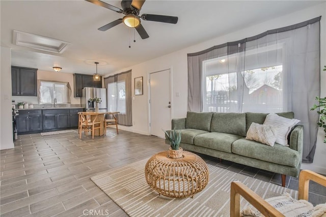 living area with attic access, a ceiling fan, and light wood finished floors