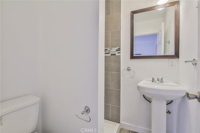 full bathroom featuring tiled shower and toilet