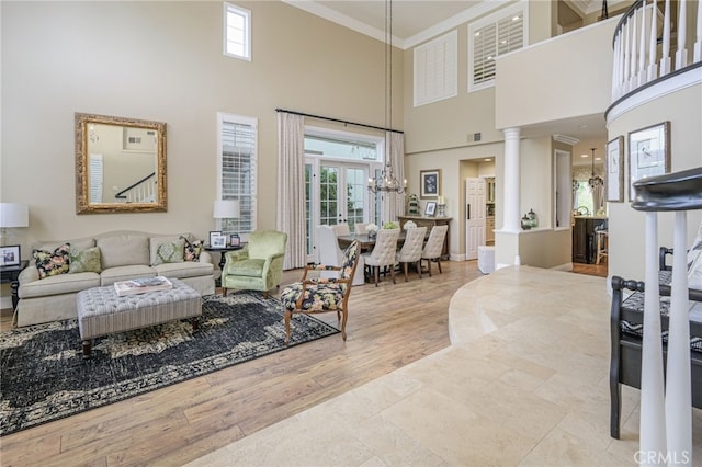 living area with a wealth of natural light, a high ceiling, ornate columns, and ornamental molding