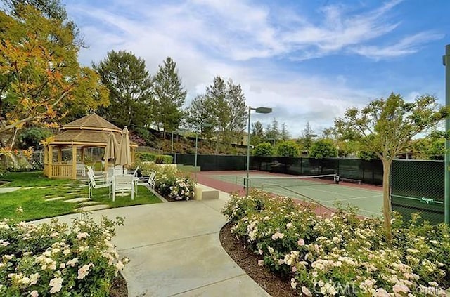view of tennis court with fence and a gazebo