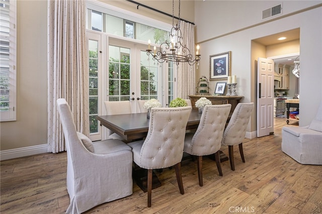 dining room featuring visible vents, french doors, light wood-style floors, baseboards, and a chandelier