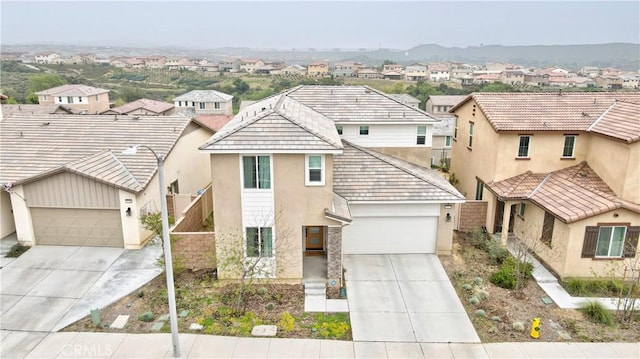 traditional home with a garage, stucco siding, driveway, and a residential view