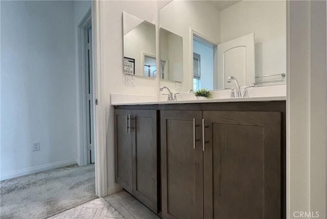 bathroom with baseboards, double vanity, and a sink