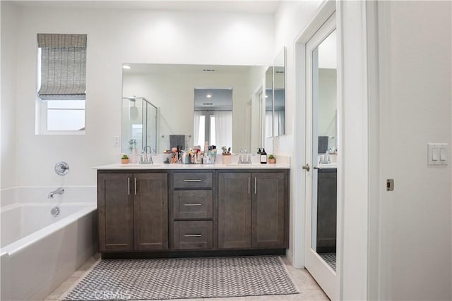 bathroom with double vanity, a sink, a bath, and a wealth of natural light