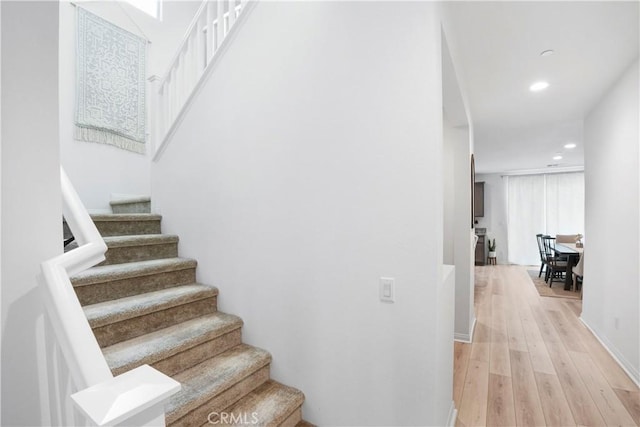 staircase featuring recessed lighting, baseboards, and wood finished floors