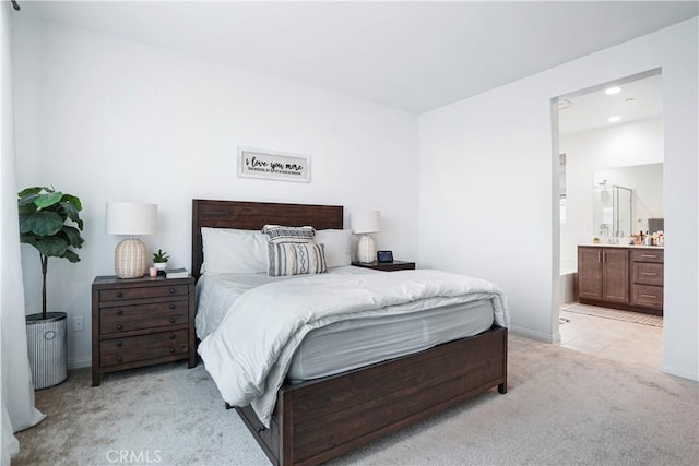bedroom with baseboards, recessed lighting, ensuite bath, and light colored carpet
