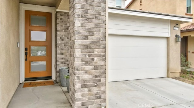 property entrance featuring a garage and stucco siding