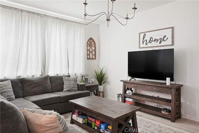 living area featuring an inviting chandelier, baseboards, wood finished floors, and a healthy amount of sunlight