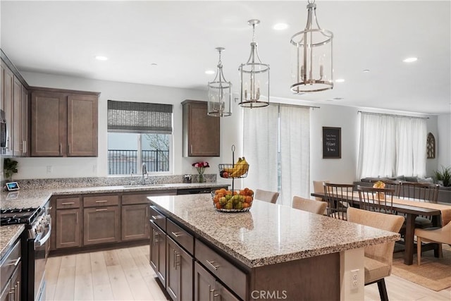 kitchen featuring recessed lighting, a sink, stainless steel gas range oven, and light wood-type flooring