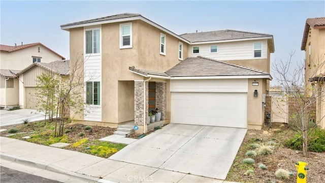 traditional-style house with an attached garage, stucco siding, a tile roof, and concrete driveway