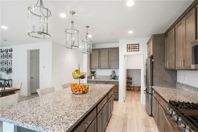 kitchen with recessed lighting, light stone counters, and stainless steel appliances