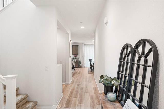 hall featuring stairs, recessed lighting, baseboards, and light wood-style flooring
