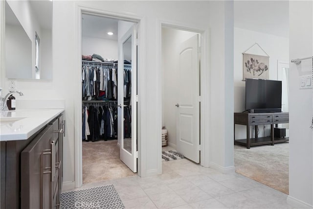 bathroom featuring a walk in closet, baseboards, and vanity