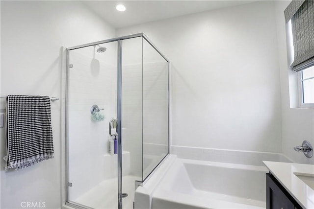 bathroom featuring vanity, a shower stall, and a garden tub