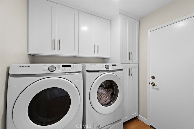 laundry area with cabinet space, independent washer and dryer, and wood finished floors