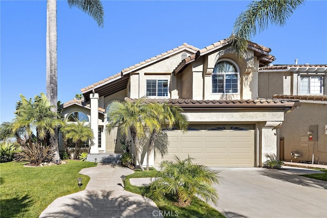mediterranean / spanish house featuring stucco siding, concrete driveway, and a tiled roof