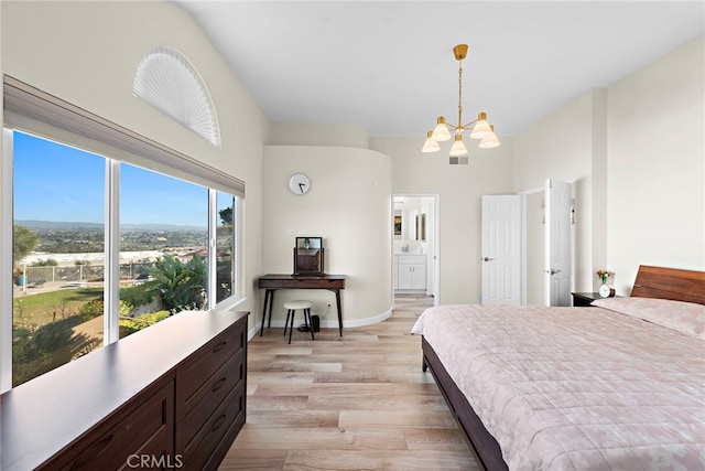 bedroom featuring a towering ceiling, visible vents, light wood-style floors, a chandelier, and ensuite bathroom
