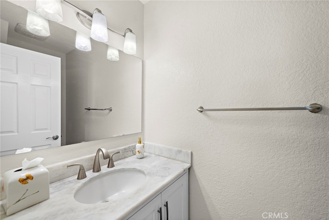 bathroom with a textured wall and vanity