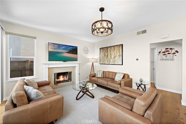living area with baseboards, wood finished floors, visible vents, and a fireplace
