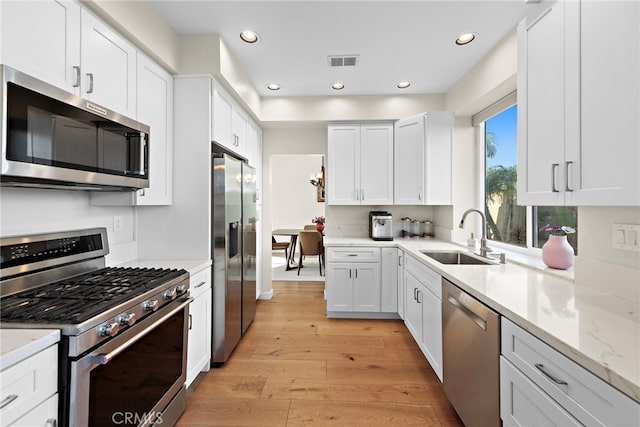 kitchen featuring a sink, light wood-type flooring, visible vents, white cabinetry, and appliances with stainless steel finishes