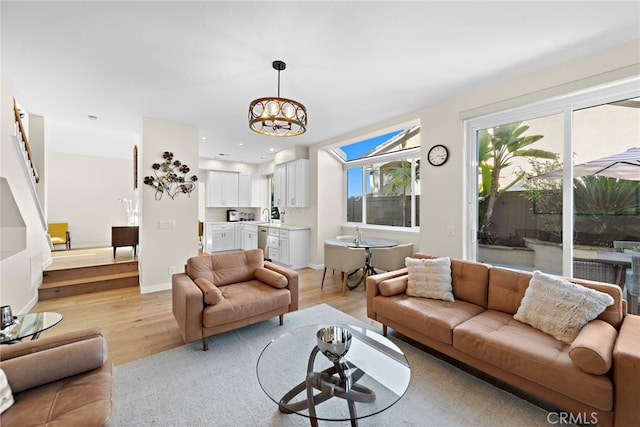 living room featuring light wood-type flooring, baseboards, and an inviting chandelier