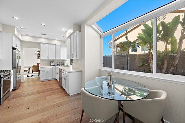 kitchen with a sink, light wood finished floors, light countertops, appliances with stainless steel finishes, and recessed lighting